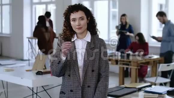 年轻的高加索商务女性穿着正式的衣服抚摸着她卷曲的头发认真专注地看着现代办公室视频的预览图