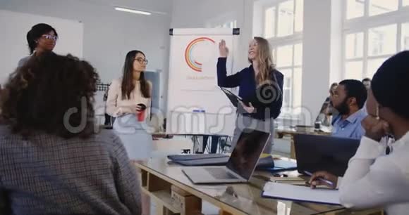 成功的美丽高加索商务女性与文件夹激励年轻的多民族办公室同事团队视频的预览图