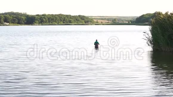 渔夫拿着鱼竿站在水里河湾的渔夫视频的预览图