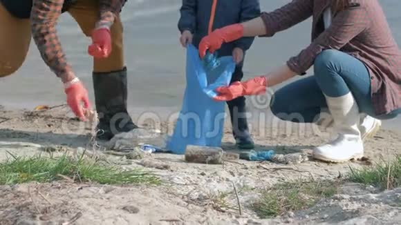 停止塑料年轻的家庭带着小男孩戴着橡胶手套在清理脏东西的同时在垃圾袋里收集垃圾视频的预览图