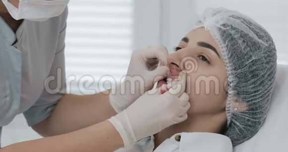 美容医生的手在隆唇后按摩病人嘴唇关门视频的预览图