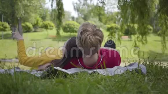 年轻快乐的一对相爱的情侣一起在美丽盛开的花园或公园里野餐放松和微笑视频的预览图