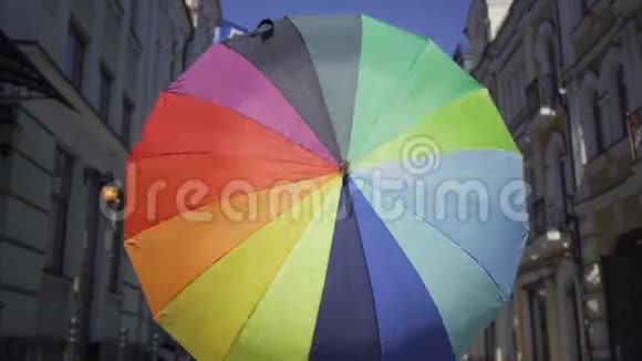 肖像年轻女子看着相机拿着五彩伞站在街上时尚迷人视频的预览图