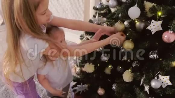 两个孩子在家玩挂在圣诞树上的玩具视频的预览图