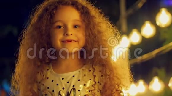 一个可爱的欧洲卷发小女孩的肖像一个孩子看着相机在背景下甜美地微笑着视频的预览图
