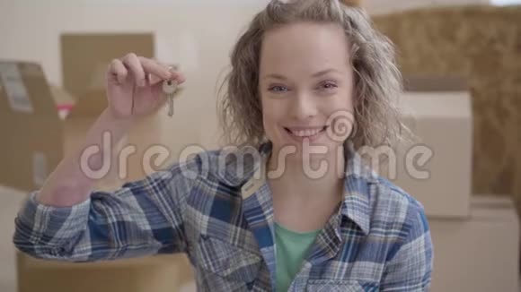 一个穿着格子衬衫的可爱女人的画像展示了从房子里拿出来的钥匙她微笑着看着镜头积极的女人动作视频的预览图