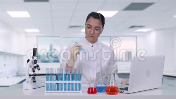 女研究员检查试管中的液体女科学家进行医学研究并写出结果视频的预览图