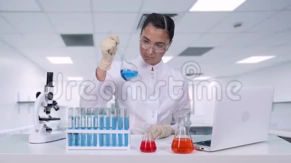一位女性研究员分析瓶中的液体并进行临床试验女科学家进行遗传视频的预览图