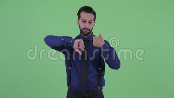 困惑的年轻留胡子的波斯商人在竖起大拇指和竖起大拇指之间做出选择视频的预览图