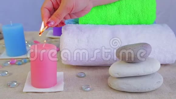 女人在水疗沙龙里用毛巾和石头点燃桌子上的蜡烛视频的预览图
