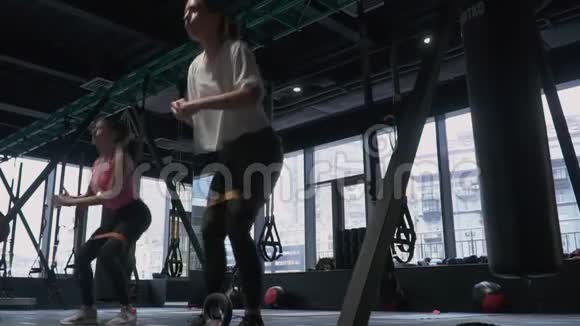 一群精力充沛的妇女在健身房里用大的落地窗吊腿蹲着视频的预览图
