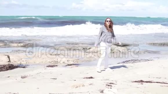 在海边沙滩上散步的女人视频的预览图