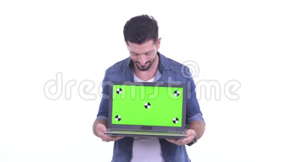 快乐的年轻有胡子的时髦男人一边说一边展示笔记本电脑视频的预览图
