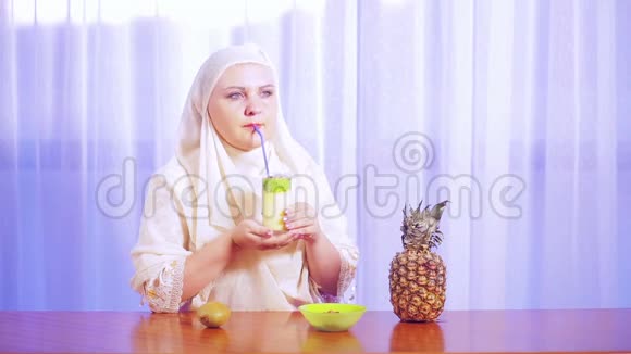 一位年轻的穆斯林妇女戴着一条轻围巾用吸管喝着水果奶昔视频的预览图