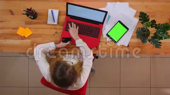 在笔记本电脑上在线购物的白种人年轻员工的特写镜头平板电脑上放着绿色屏幕视频的预览图