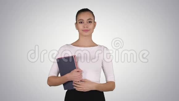 美丽的年轻女子带着笔记本走在梯度背景上视频的预览图
