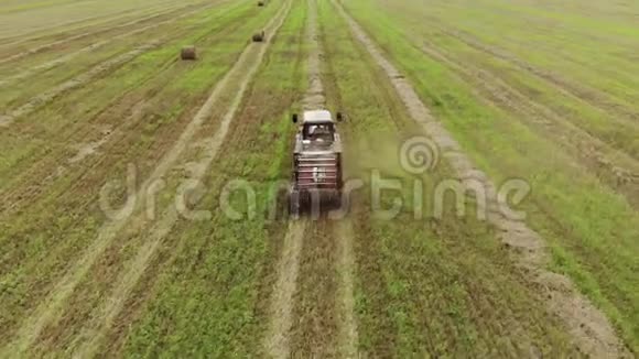 一种带有圆形打包机的拖拉机的鸟瞰图它可以在收获的土地上制造成捆的稻草这是一种农业综合企业的概念视频的预览图