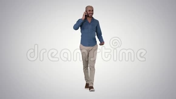 年轻的阿拉伯男人在电话里走来走去在渐变的背景下微笑视频的预览图