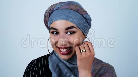 年轻美丽的阿拉伯女人笑着她的手靠近她的脸在孤立的白色背景视频的预览图