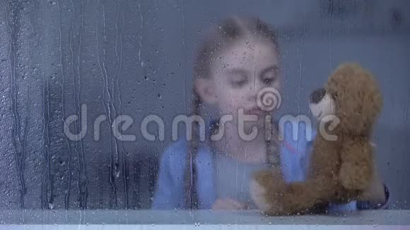 寂寞的小女孩在下雨天在家玩玩具熊没有朋友视频的预览图