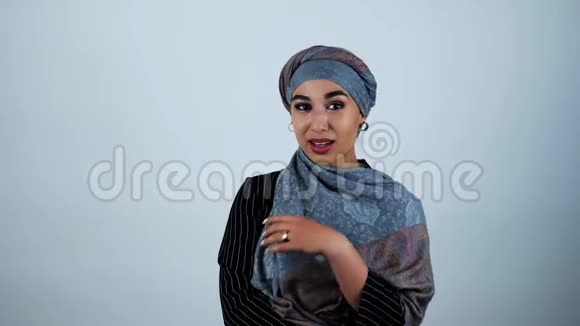 年轻美丽的阿拉伯女人微笑着调整她的头巾她的手在孤立的白色背景上移动视频的预览图