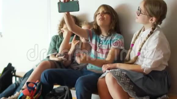 课间休息时青少年在智能手机学校走廊的摄像头上拍照带手提箱的儿童视频的预览图