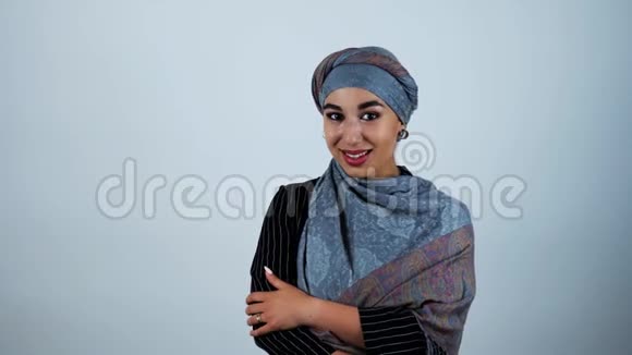 年轻美丽的阿拉伯女人微笑着在与世隔绝的白色背景下感到有点害羞视频的预览图