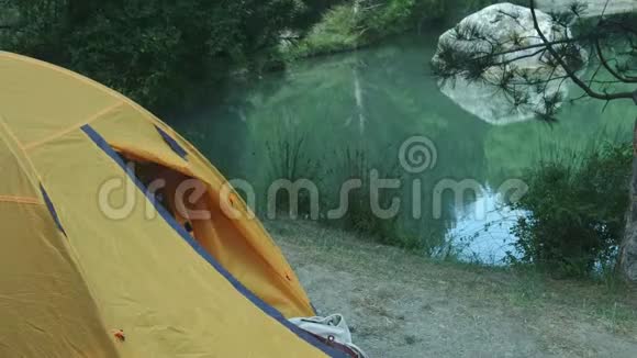 青年徒步旅行者沿着池塘走在后面的行军背包上一个人从绿色森林的帐篷里走出来视频的预览图