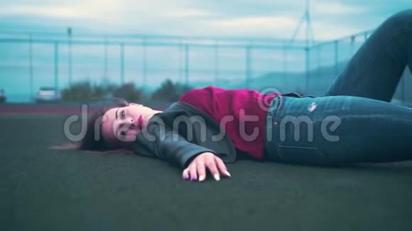 一个美丽而热情的女孩躺在法庭的地板上一个年轻的女人躺在球场的绿色表面上视频的预览图