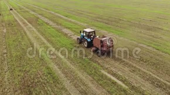 一种带有圆形打包机的拖拉机的鸟瞰图它可以在收获的土地上制造成捆的稻草这是一种农业综合企业的概念视频的预览图