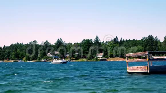 美丽的蓝色北明尼苏达湖有树木海岸线和家园在阳光明媚的一天一艘浮舟接近视频的预览图
