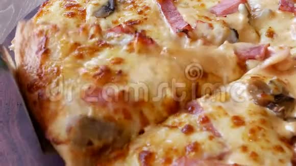 将新鲜的热蘑菇火腿奶酪比萨饼片与融化的奶酪一起用木盘舀取出视频的预览图