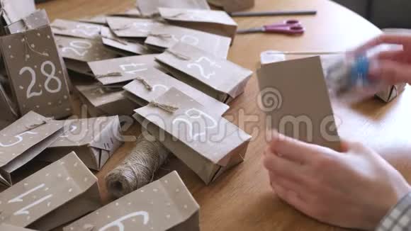 女人把玩具和糖果放在袋子里制作圣诞来临日历特写双手视频的预览图