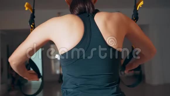 女孩在大厅里使用TRX循环锻炼胸部肌肉TRX向上推视频的预览图