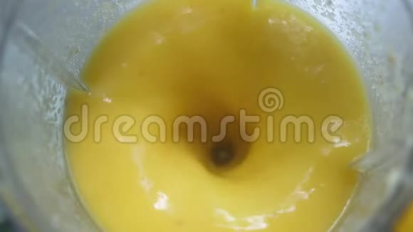 在搅拌机里做新鲜芒果水果奶昔健康生活方式的概念近距离慢动作俯视视频的预览图