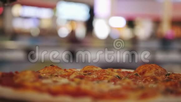 在披萨上倒入油的特写镜头背景上有模糊的灯光慢动作视频的预览图