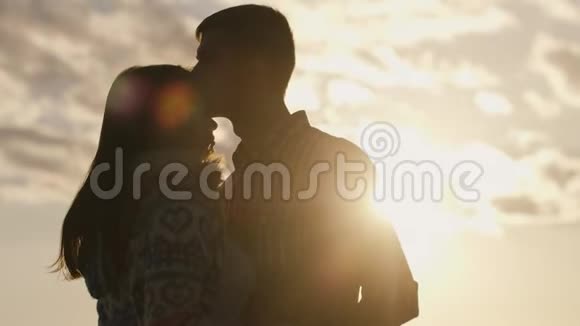 一对相爱的年轻夫妇在天空和太阳的背景下互相看着对方的剪影视频的预览图
