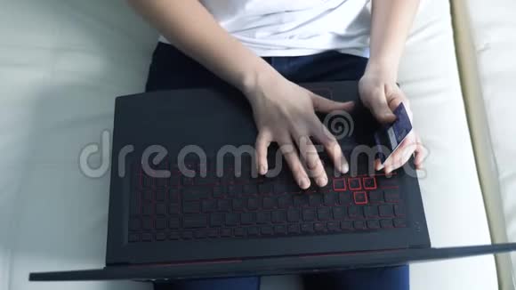 女孩用笔记本电脑数字平板电脑制作网上销售购物概念黑发女人躺在沙发上看店视频的预览图