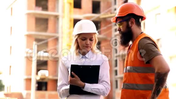 两名土木工程师持有计划并检查施工现场男女建筑工人视频的预览图