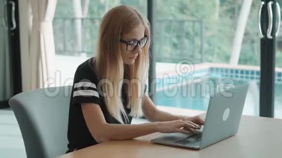 女人坐在家里对着电脑打字旁边是从窗外的游泳池视频的预览图