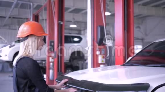 汽车修理服务戴着安全帽的年轻女子打开汽车引擎盖看着里面视频的预览图