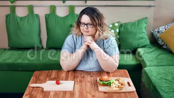 在美国快餐和新鲜有机蔬菜之间选择深思熟虑的饮食肥胖女人视频的预览图