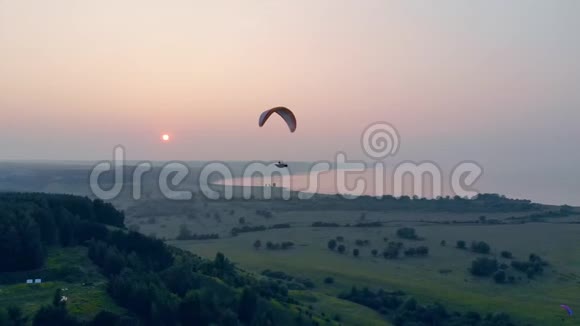在日落背景下运动员在空中滑翔伞飞行滑翔伞动作极限运动理念视频的预览图