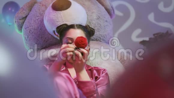 穿着粉红色睡衣的快乐女孩玩戒指看着相机她很高兴视频的预览图