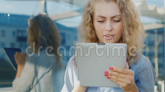 一位迷人的年轻女子的肖像使用平板电脑靠近城市的镜子墙积极的情绪视频的预览图