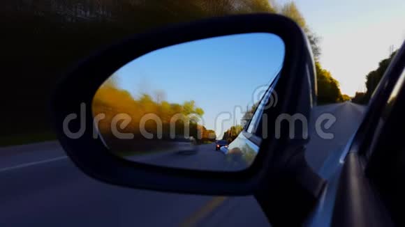运动模糊版在日落时驾驶乡村道路侧镜驾驶员视角POV向下侧视镜视频的预览图