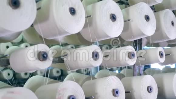 纺织厂设备在工作大的筒管盘绕着螺纹旋转在工厂的机架上视频的预览图