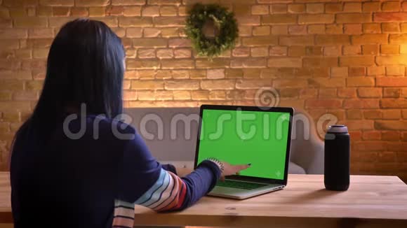 在舒适的公寓里室内有绿色屏幕的年轻漂亮女性在笔记本电脑上打字的特写后景视频的预览图