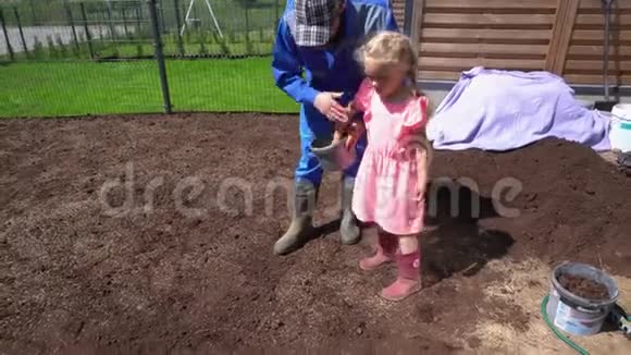 女儿帮助父亲在联排别墅院子里播种草坪草手持视频的预览图