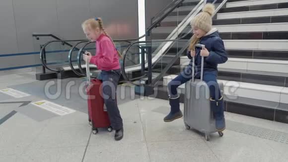 在自动扶梯背景下十几岁的女孩坐在机场的手提箱上视频的预览图